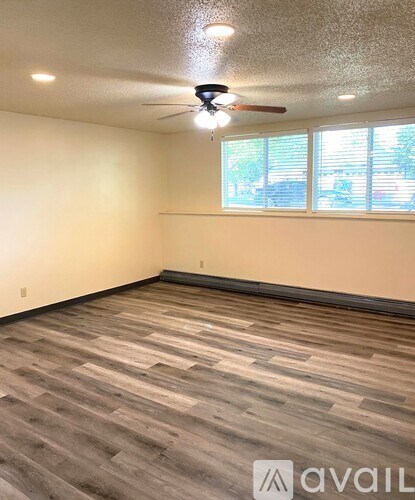 A room with a ceiling fan and wooden flooring.