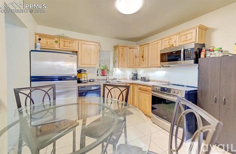A kitchen with wooden cabinets and a glass table.