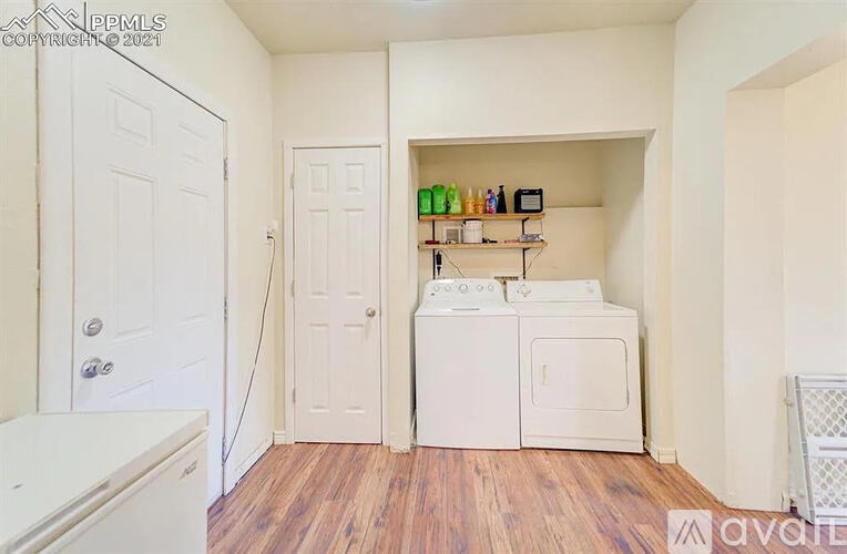 A small kitchen with a white fridge, a white oven, and a white door.