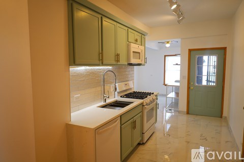 A kitchen with green cabinets and a white stove top oven.