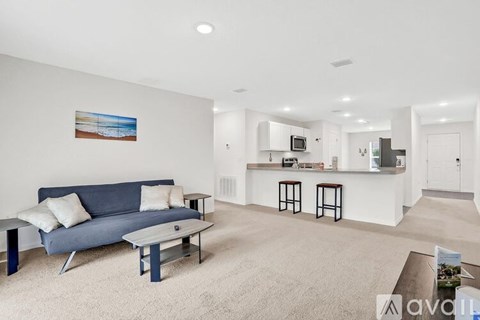 A living room with a blue couch and a painting on the wall.