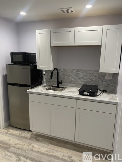 A kitchen with white cabinets and a black microwave.