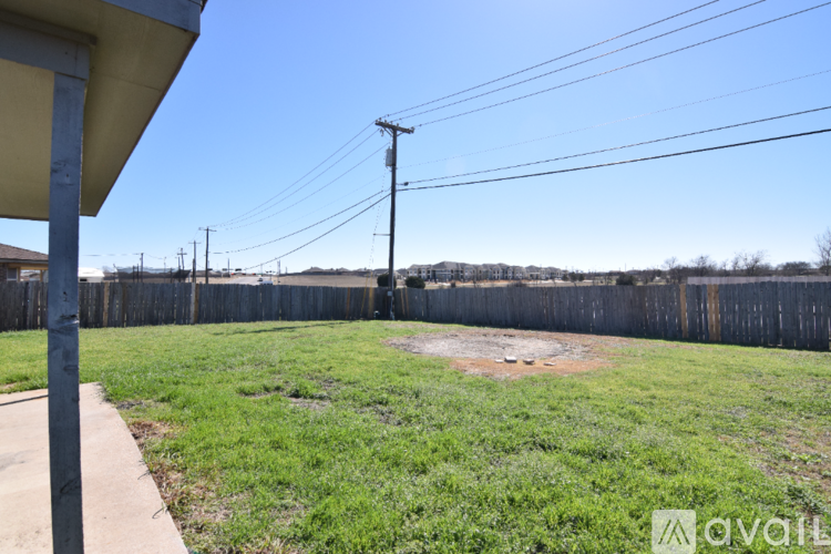 A grassy field with a wooden fence and power lines in the distance.