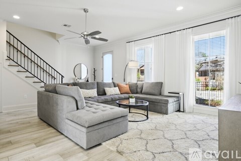 A living room with a grey couch and a round mirror on the wall.
