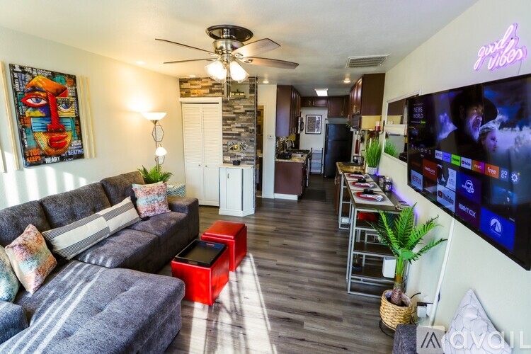 A living room with a grey sofa and a TV on the wall.