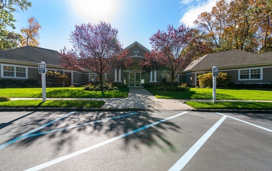 a parking lot in front of a house with trees