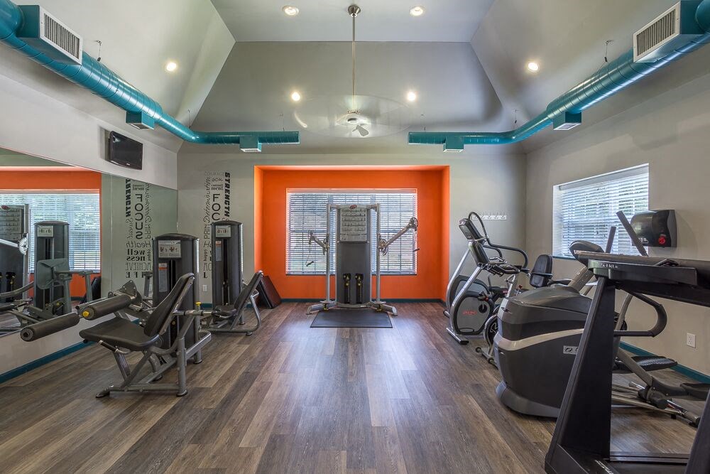 a gym with cardio machines and weights on a hard wood floor