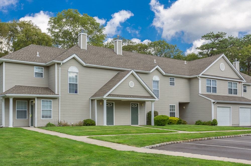 the front of a house with a green lawn and trees
