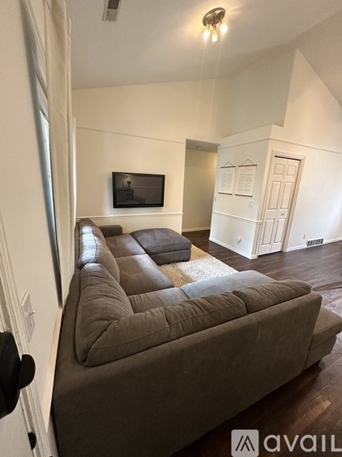 A living room with a brown couch and a flat screen TV mounted on the wall.