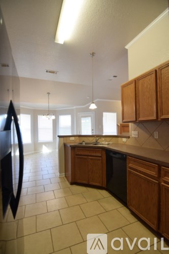 A kitchen with wooden cabinets and a black refrigerator.