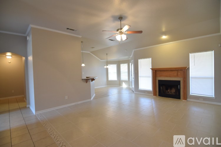 A spacious living room with a fireplace and a fan.