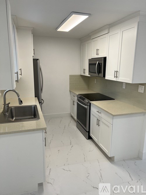 A kitchen with white cabinets and a marble countertop.