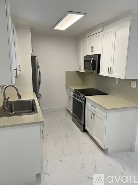 A kitchen with white cabinets and a marble countertop.