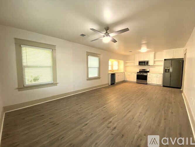 A spacious room with a ceiling fan and wooden flooring.