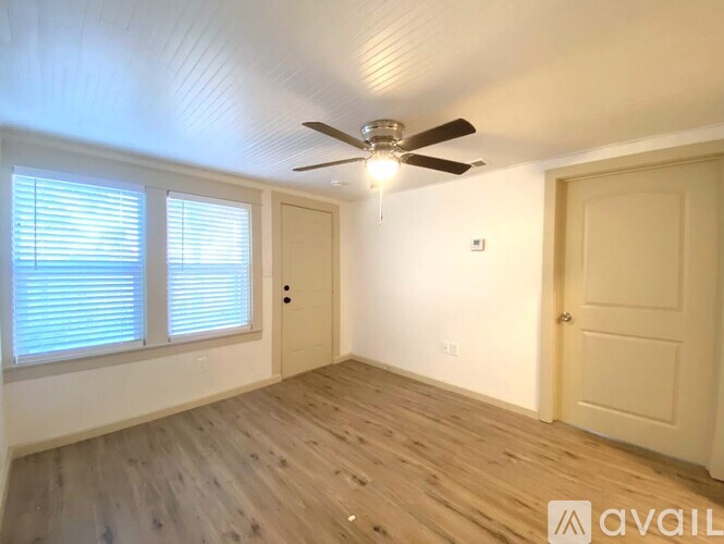A spacious room with a ceiling fan and wooden flooring.