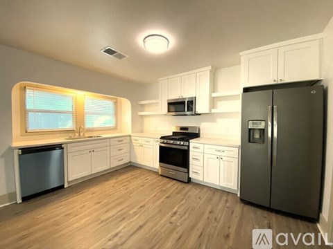 A kitchen with wooden floors and white cabinets.