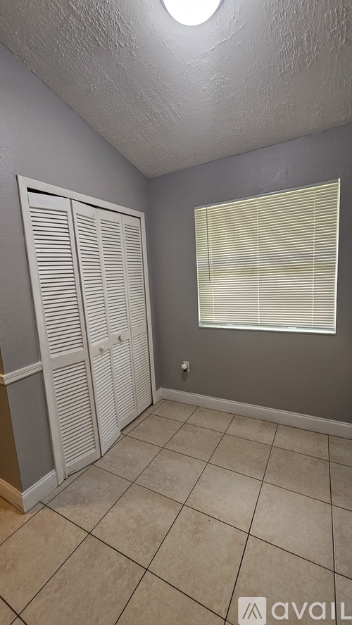 A room with a white closet and a window with blinds.