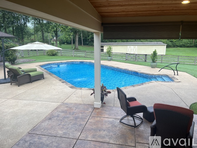 A pool surrounded by a patio with chairs and a table.