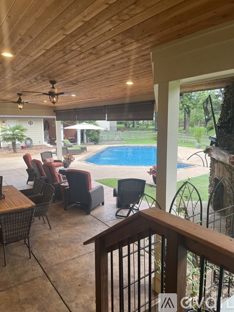A wooden deck with a table and chairs overlooking a pool.