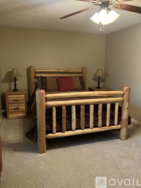 A bedroom with a bed, nightstands, and a ceiling fan.