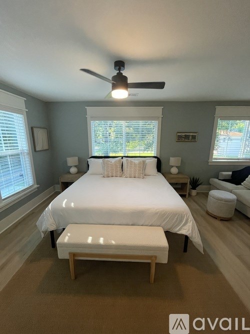 A bedroom with a bed, a bench, and a ceiling fan.