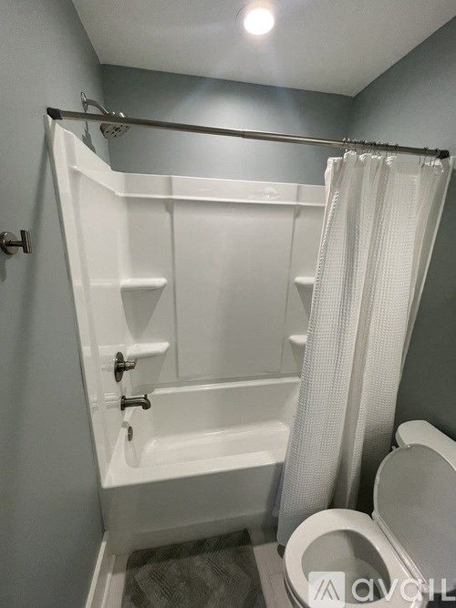 A white bathroom with a toilet, tub, and shower.