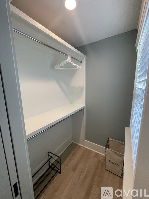A white closet with a hanger and a basket on the floor.