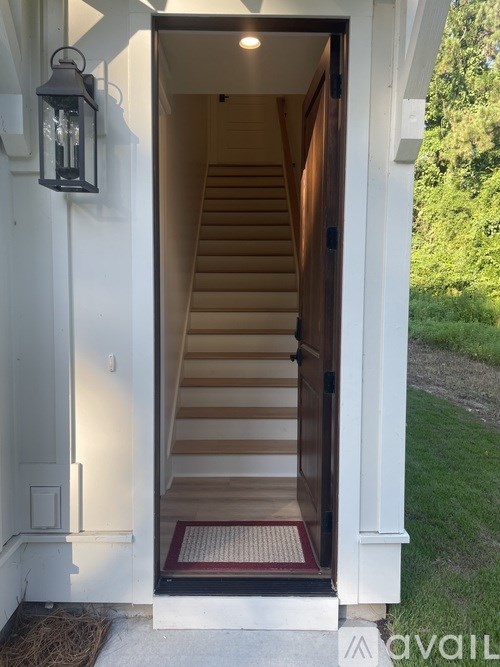 A white door with a black lantern on the wall and a wooden staircase leading to the door.