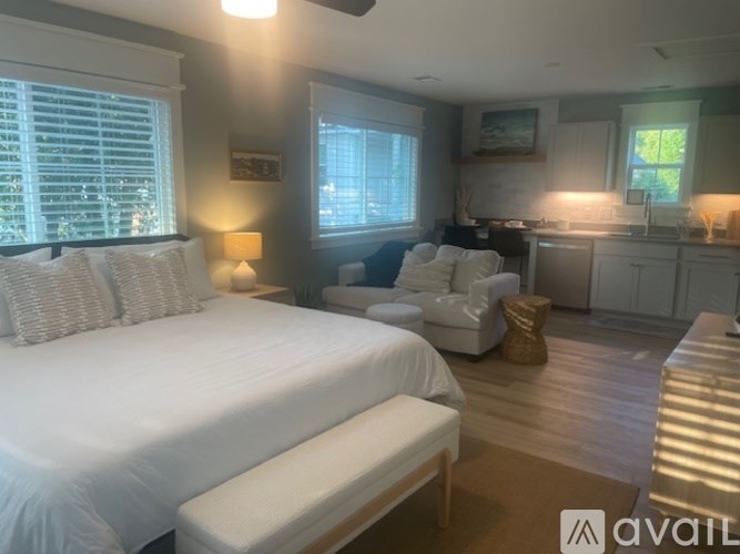 A bedroom with a large bed and a kitchen area in the background.