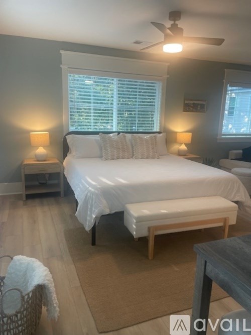 A bedroom with a bed, two lamps, and a ceiling fan.