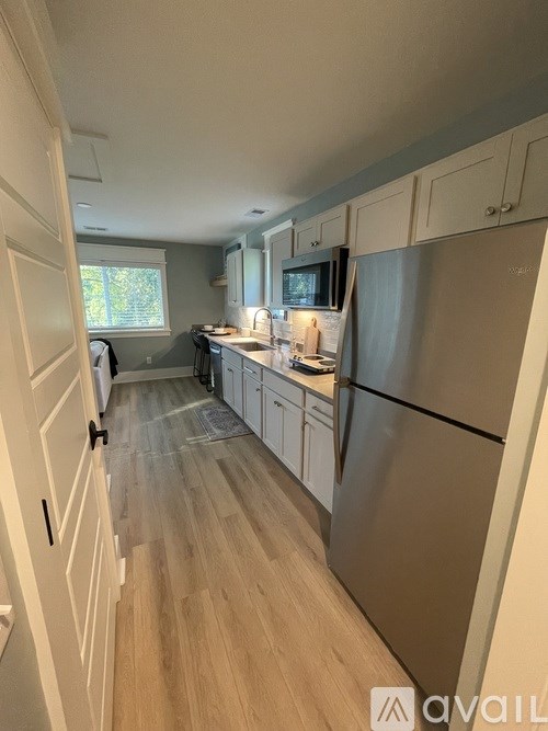 A kitchen with a refrigerator, cabinets, and a microwave.