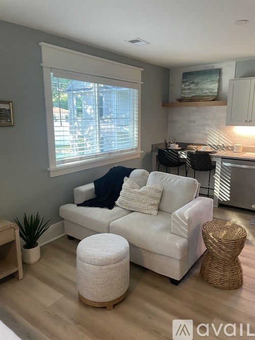 A living room with a white couch and a wicker ottoman.