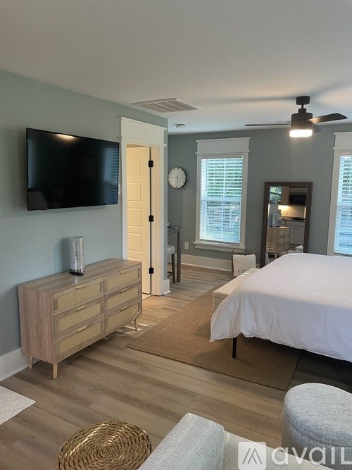 A bedroom with a bed, dresser, and a television on the wall.