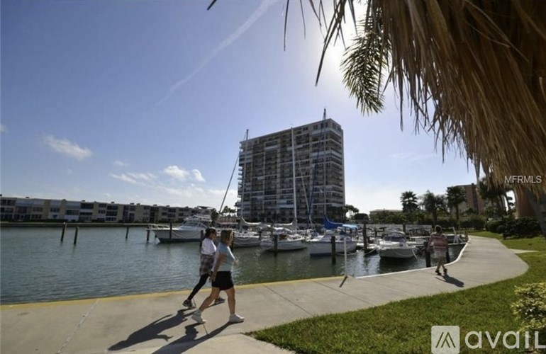 Two people walking on a sidewalk near a body of water with a building under construction in the background.