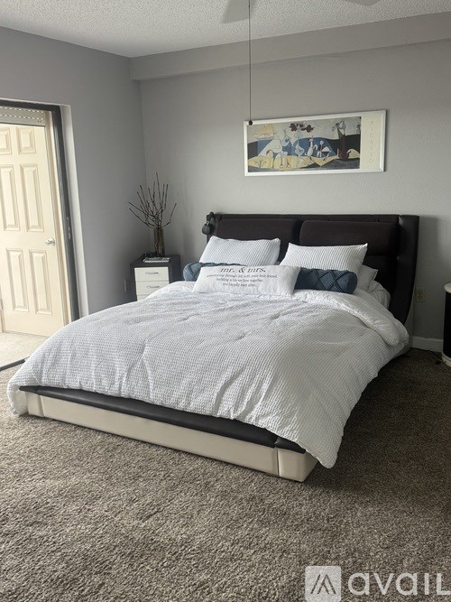 A bedroom with a large bed and a painting on the wall.