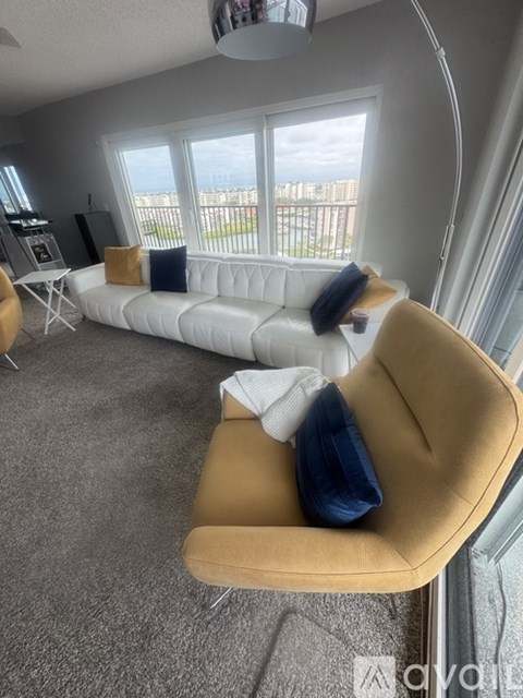 A living room with a white couch and a yellow chair.