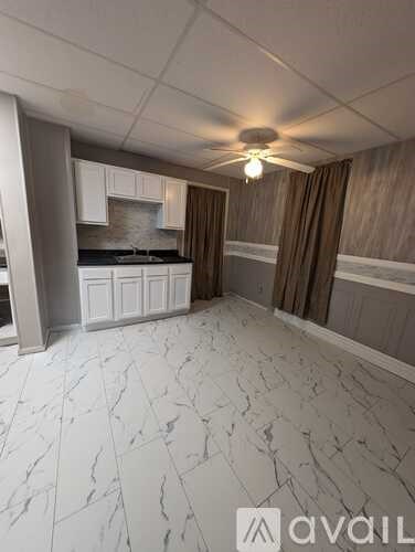 A kitchen with white marble flooring and wooden walls.