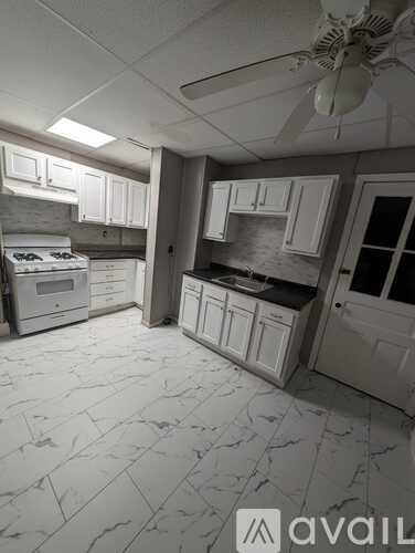 A kitchen with white cabinets and a marble floor.