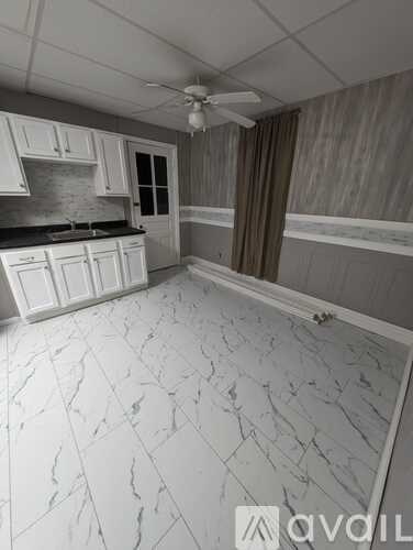 A kitchen with white marble flooring and white cabinets.