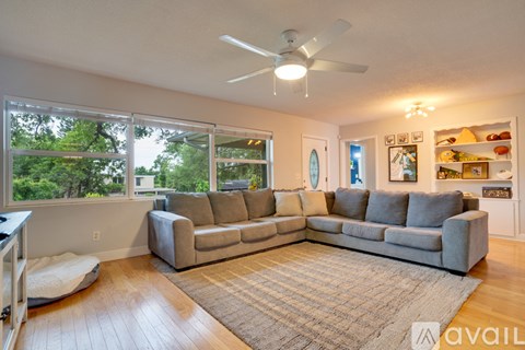 A living room with a grey sofa and a fan.