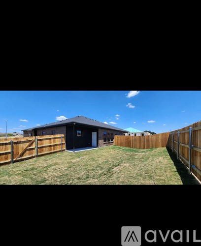 A black building with a white door is surrounded by a wooden fence.