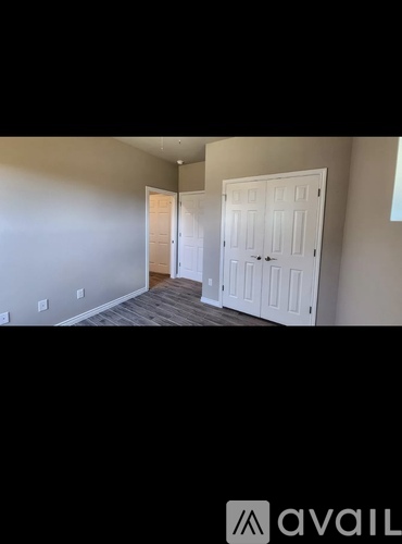 A room with two white doors and a wooden floor.