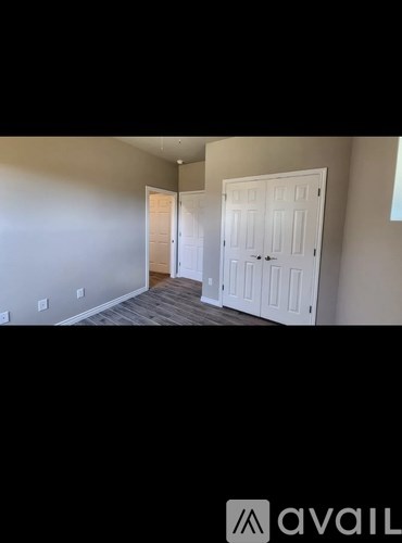 A room with two white doors and a wooden floor.