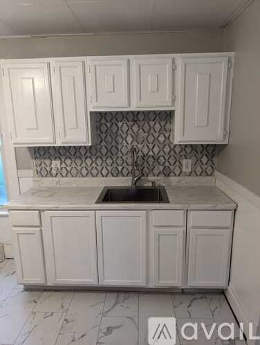 A kitchen with white cabinets and a marble countertop.
