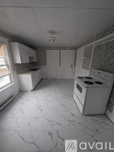 A kitchen with a white stove top oven and a white tiled floor.