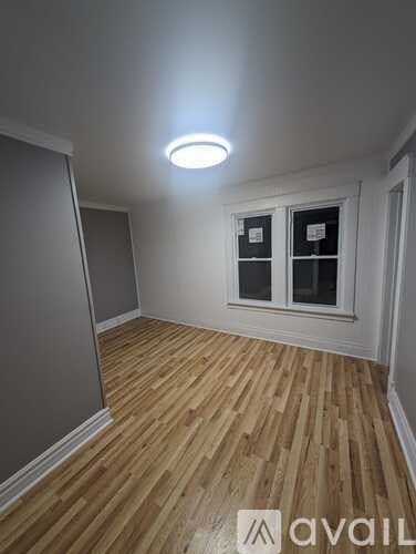 A room with wooden flooring and a window with a white frame.