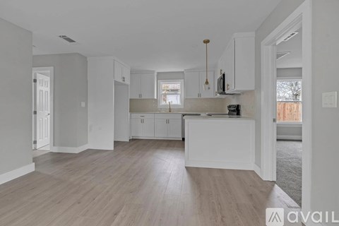 A kitchen with white cabinets and a wooden floor.