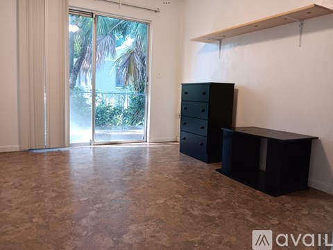 A room with a black dresser and a window with a view of trees.