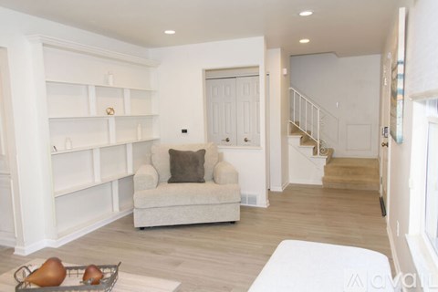 A living room with a white couch and a staircase in the background.