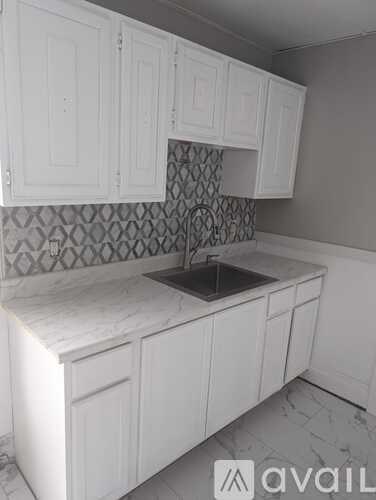 A kitchen with white cabinets and a marble countertop.